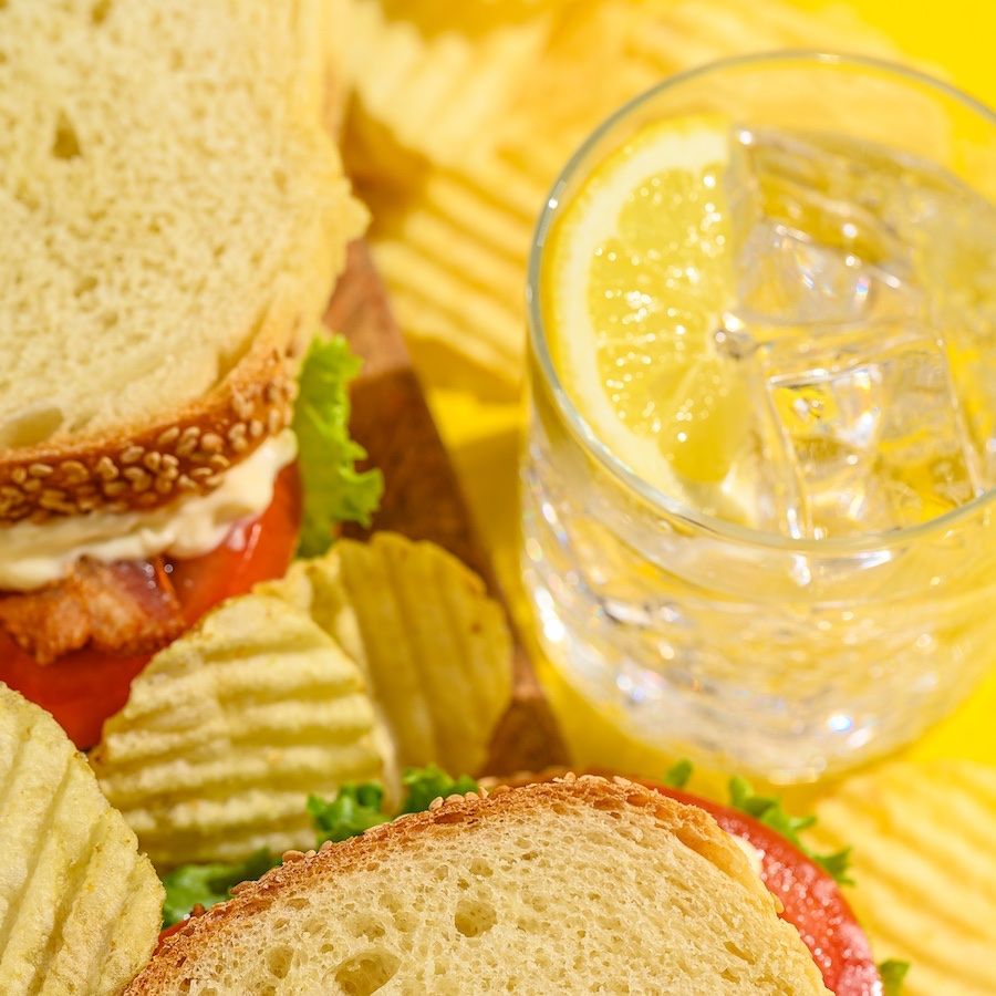 A sandwich with chips and lemonade